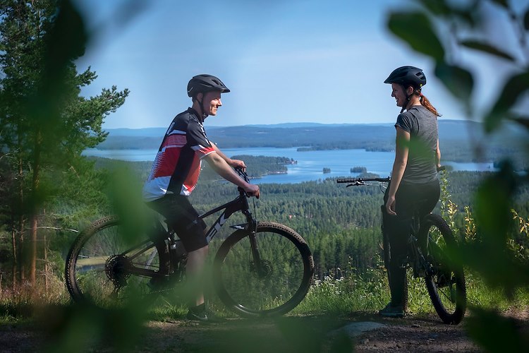 Två cyklister och utsikt över en sjö. 