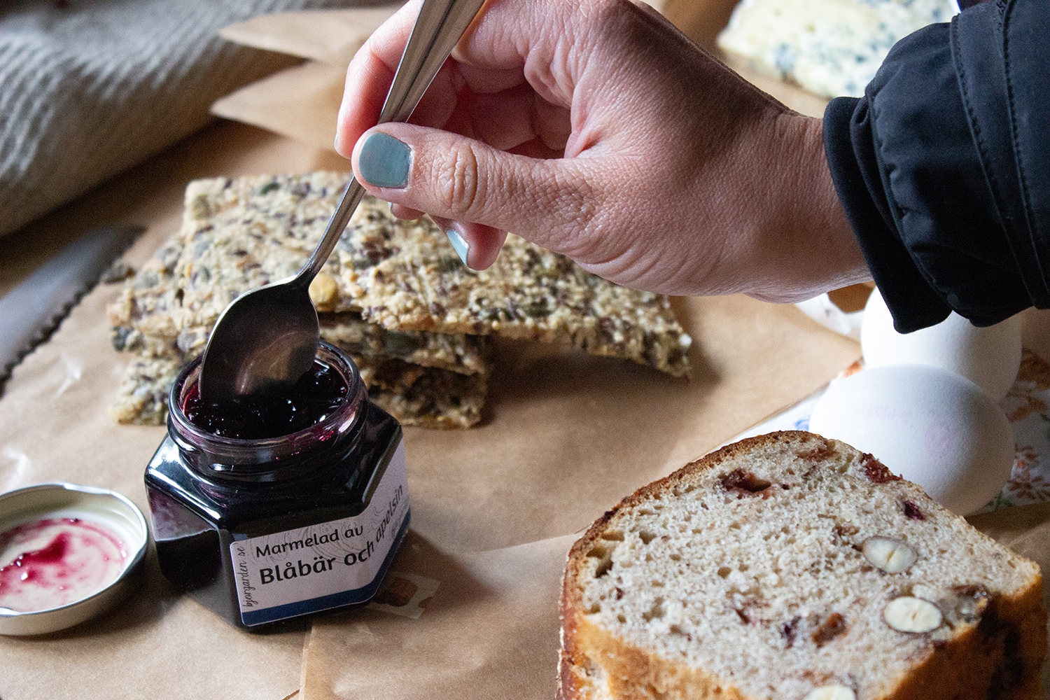 En hand tar marmelad för att bre på en smörgås.