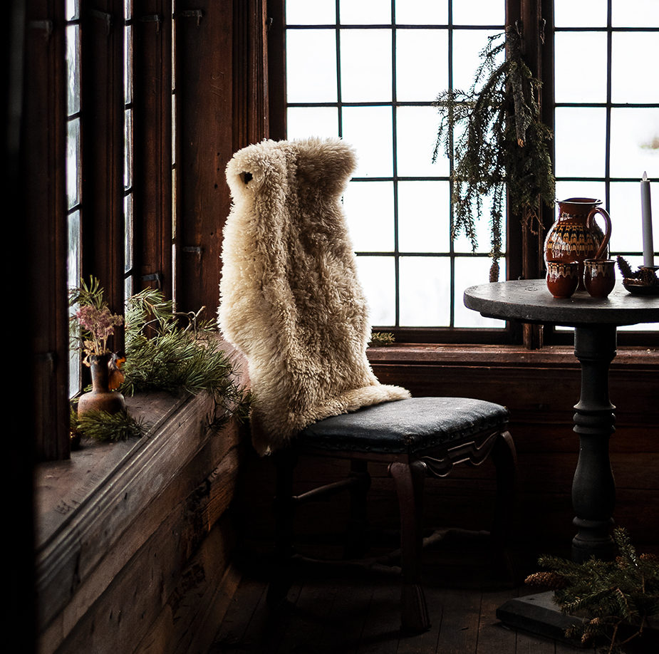 Ett fårskinn på en stol vid ett fönster.