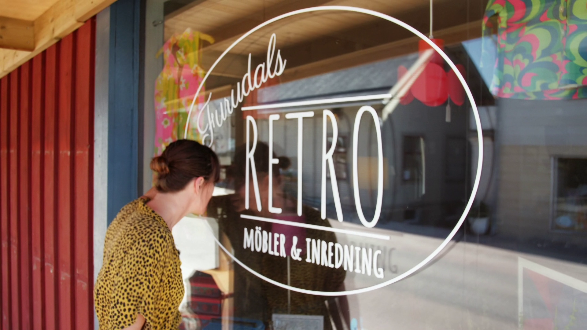 Isabelle tittar in genom ett fönster på en Retrobutik.