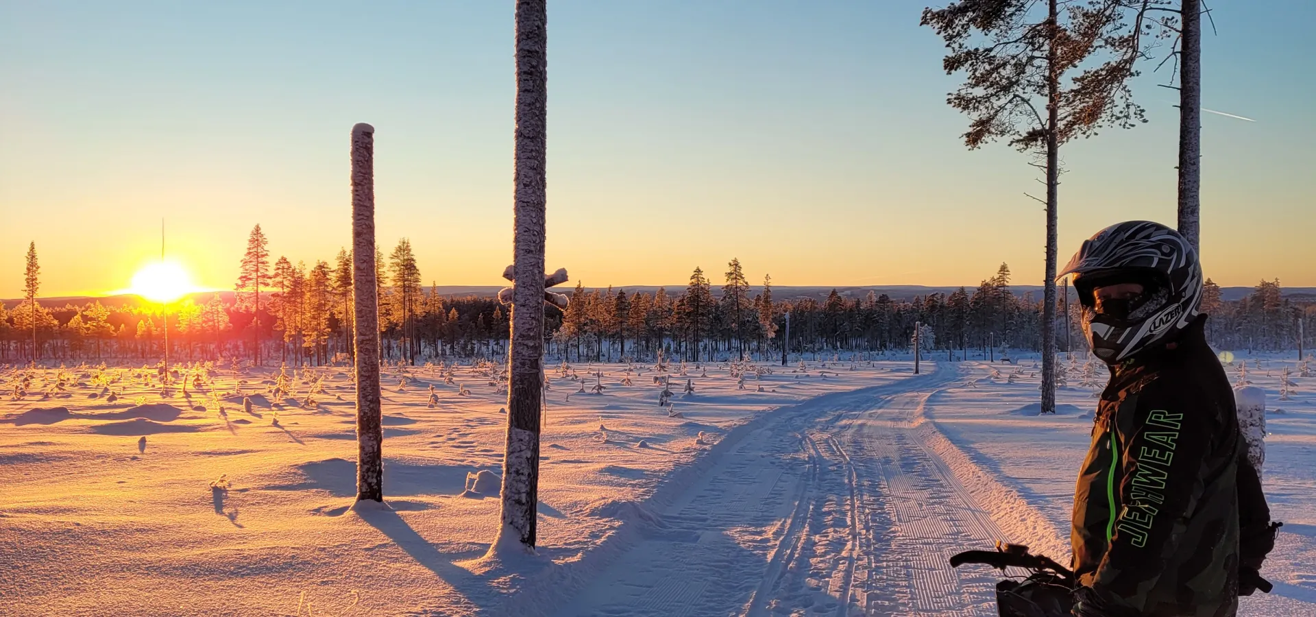 En skoteråkare vänder sig om och solen går ned i fjärran.