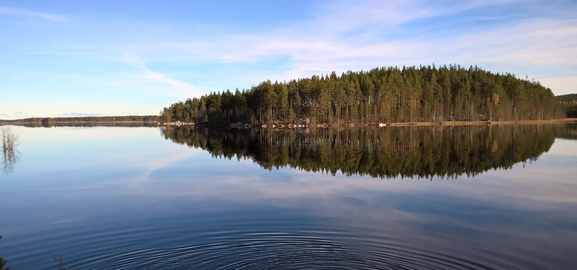 Spegelblank sjö i skymning.