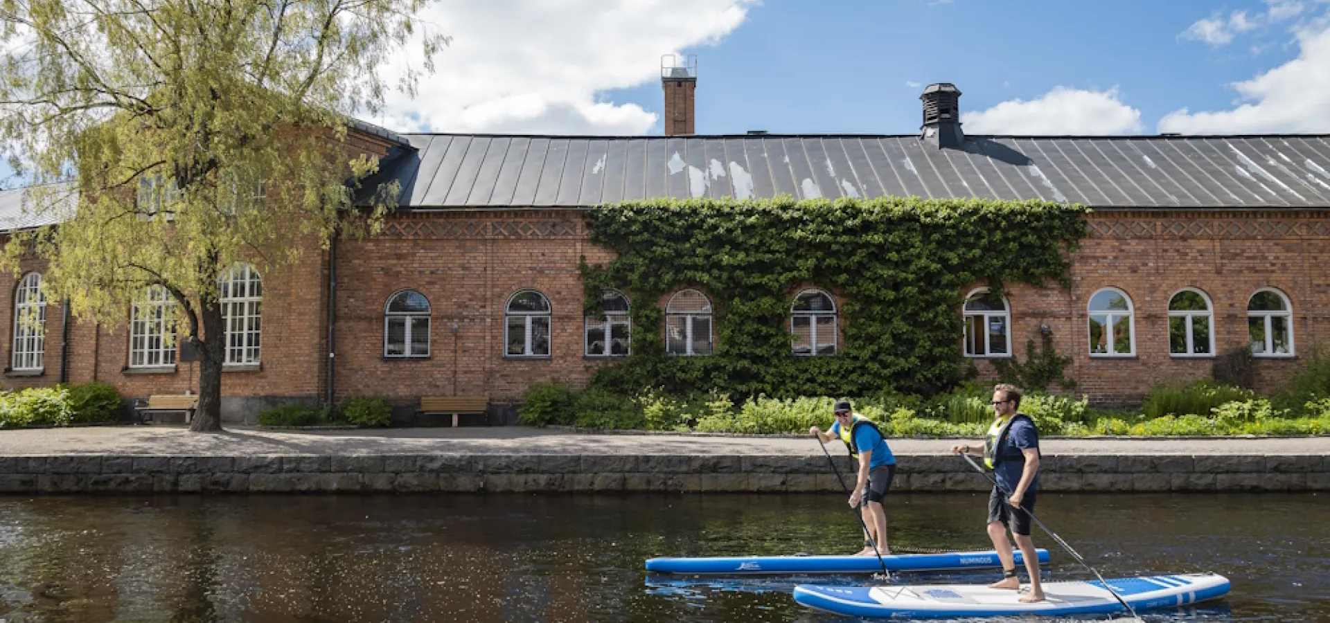 Två personer paddlar supbräda i Faluån.