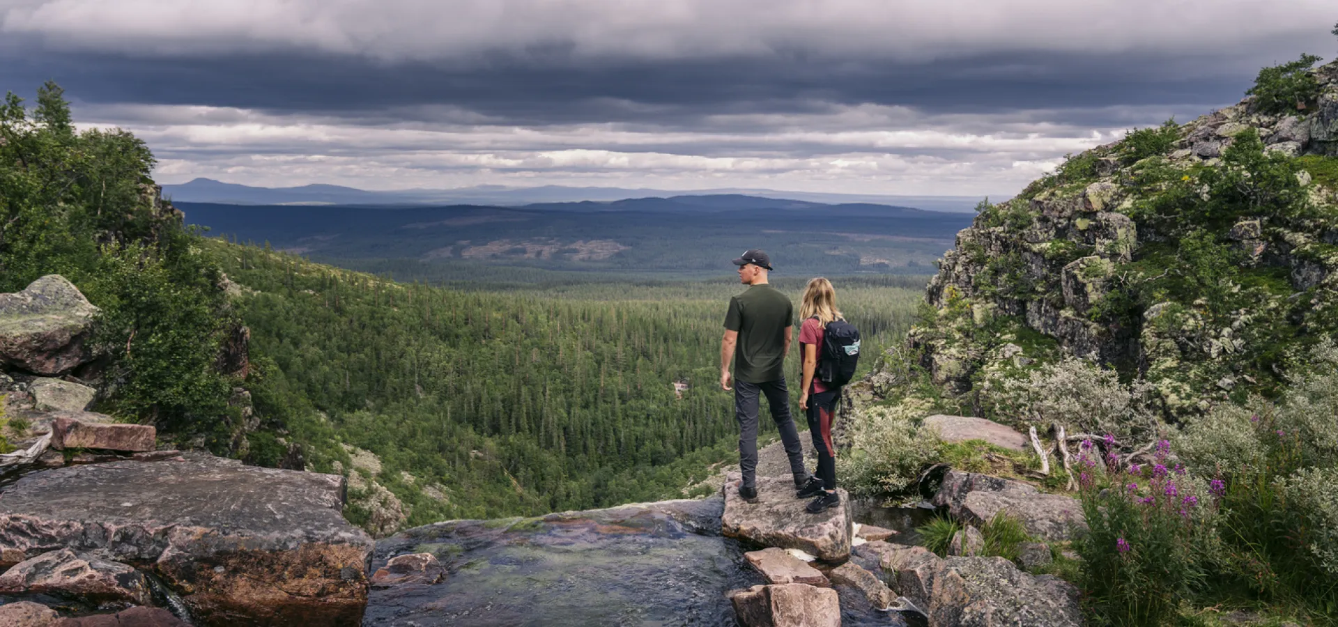 Man och kvinna blickar ut över fjällen vid Njupeskärs vattenfall.