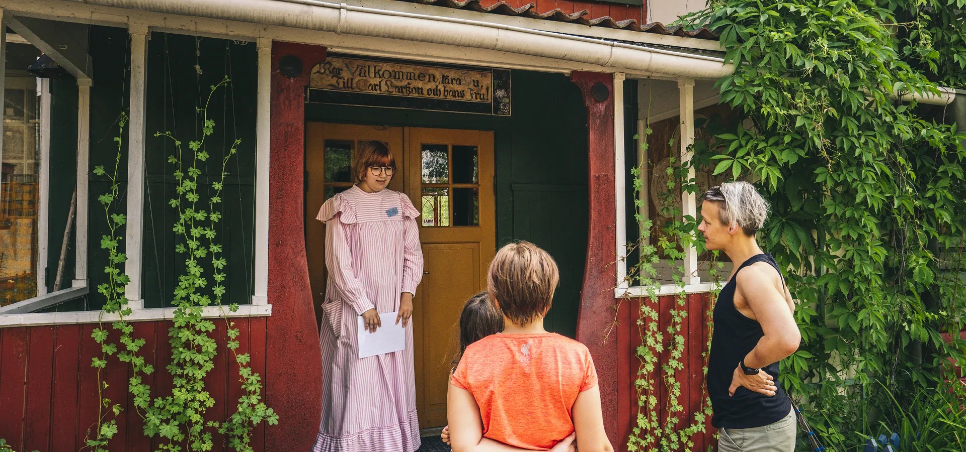 Guide som välkomnar besökare för en guidad tur inne i Carl Larsson-gården.