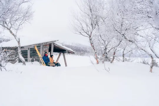 Par som sitter vid en slogbod i vintermiljö.