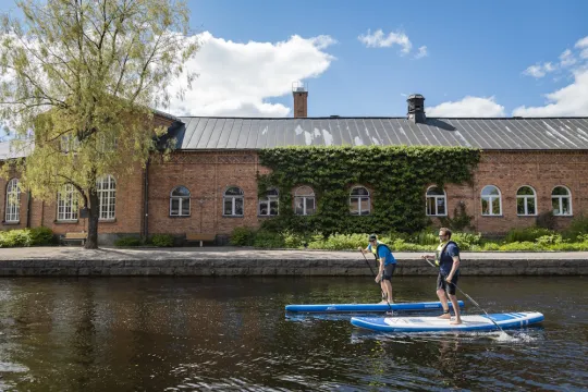 Två personer paddlar supbräda i Faluån.