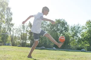 Pojke som sparkar fotboll på gräsmattan.
