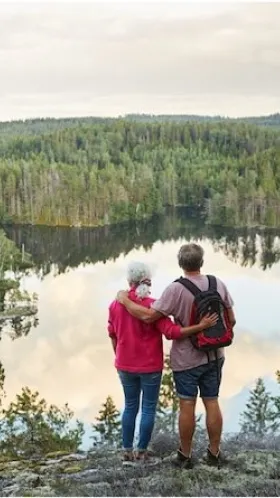 Par som står på ett berg och kollar ner på en sjö.