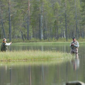 Two men in the water and doing some fly fishing.
