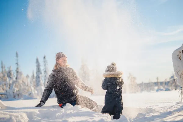 Barn och mamma leker i snö.