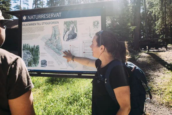 A couple looking at a hiking sign.