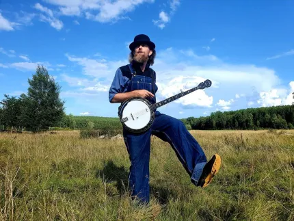 En person i en hatt som spelar en banjo på ett fält.