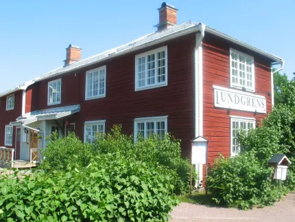 En röd träbyggnad med vita fönster och knutar, skylt Lundgrens.