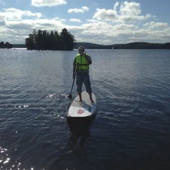 En person står på en stand up paddle board i vattnet.