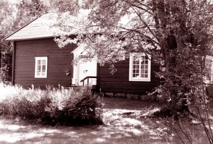 En svartvit bild på ett gammalt timmerhus.