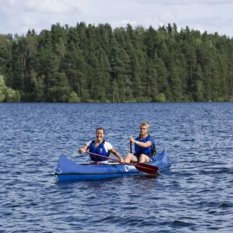 Två personer som paddlar på en sjö i en blå kanot.