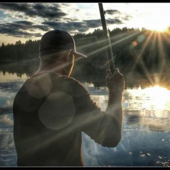 Fiskare med solnedgång som blänker i vattnet.