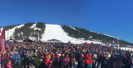 Ski slope in the background and many people in the foreground.