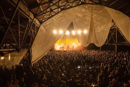 En stor publik, tyg i taket, i bakrunden en scen med strålkastare.