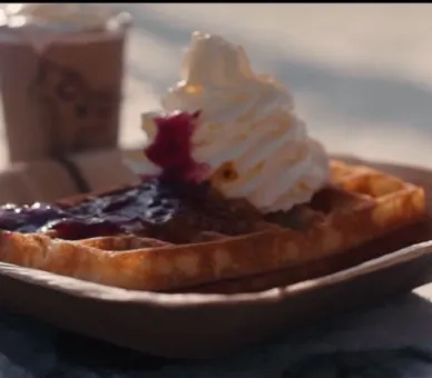 A waffle with jam and whipped cream.