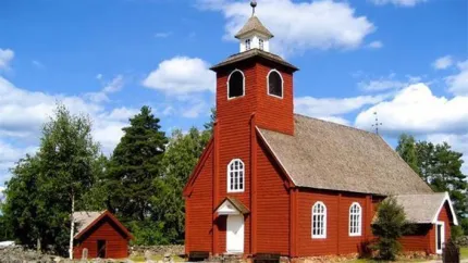 Envikens Gamla kyrka, rör träkyrka med vit port och vitt kyrktorn.
