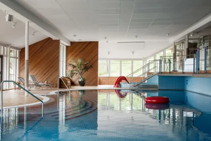A swimming pool, a red bathing ring in the pool, sun loungers, children's pool and stairs in the background.