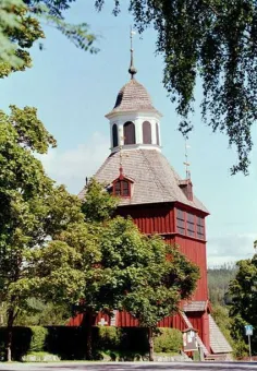En röd träkyrka med ett vitt torn.