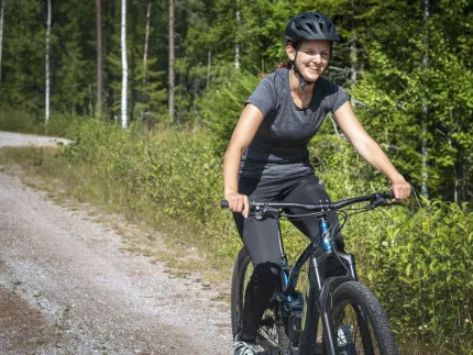 A woman cycling on a forest road.