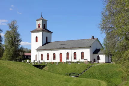 Vit kyrka med grönska omkring. 