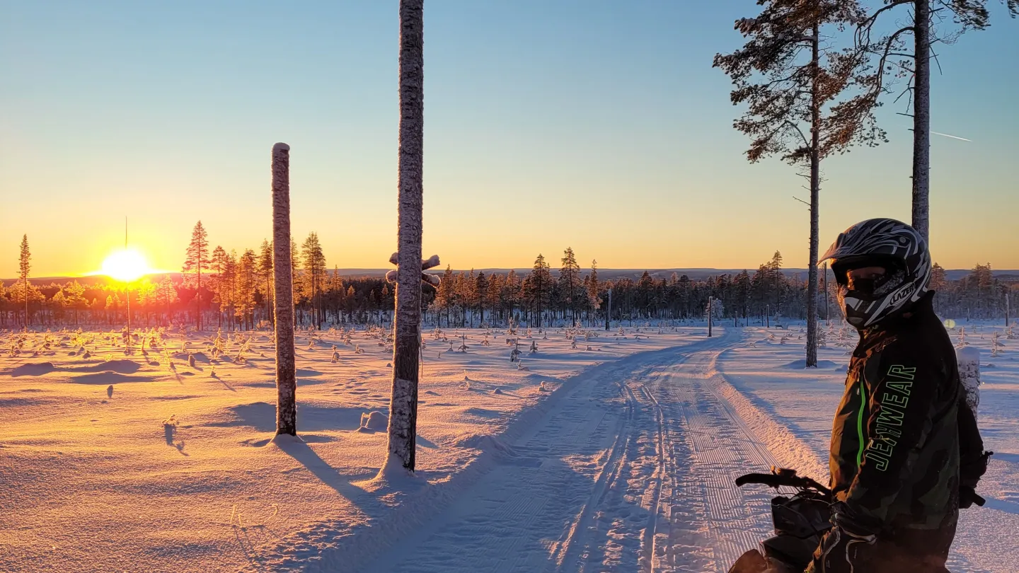 En skoteråkare vänder sig om och solen går ned i fjärran.