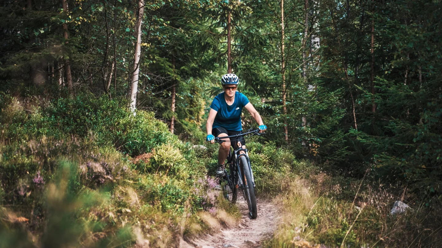 Tjej som cyklar längs en skogsled.