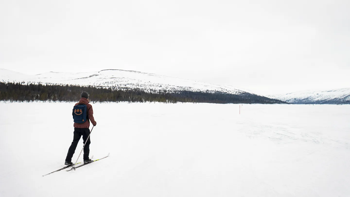 En person åker turskidor över snötäckt mark.