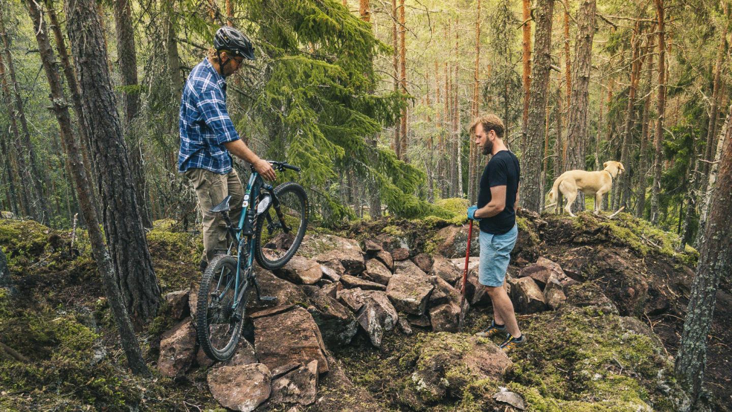 Två killar som bygger en stig för cykling i skog.