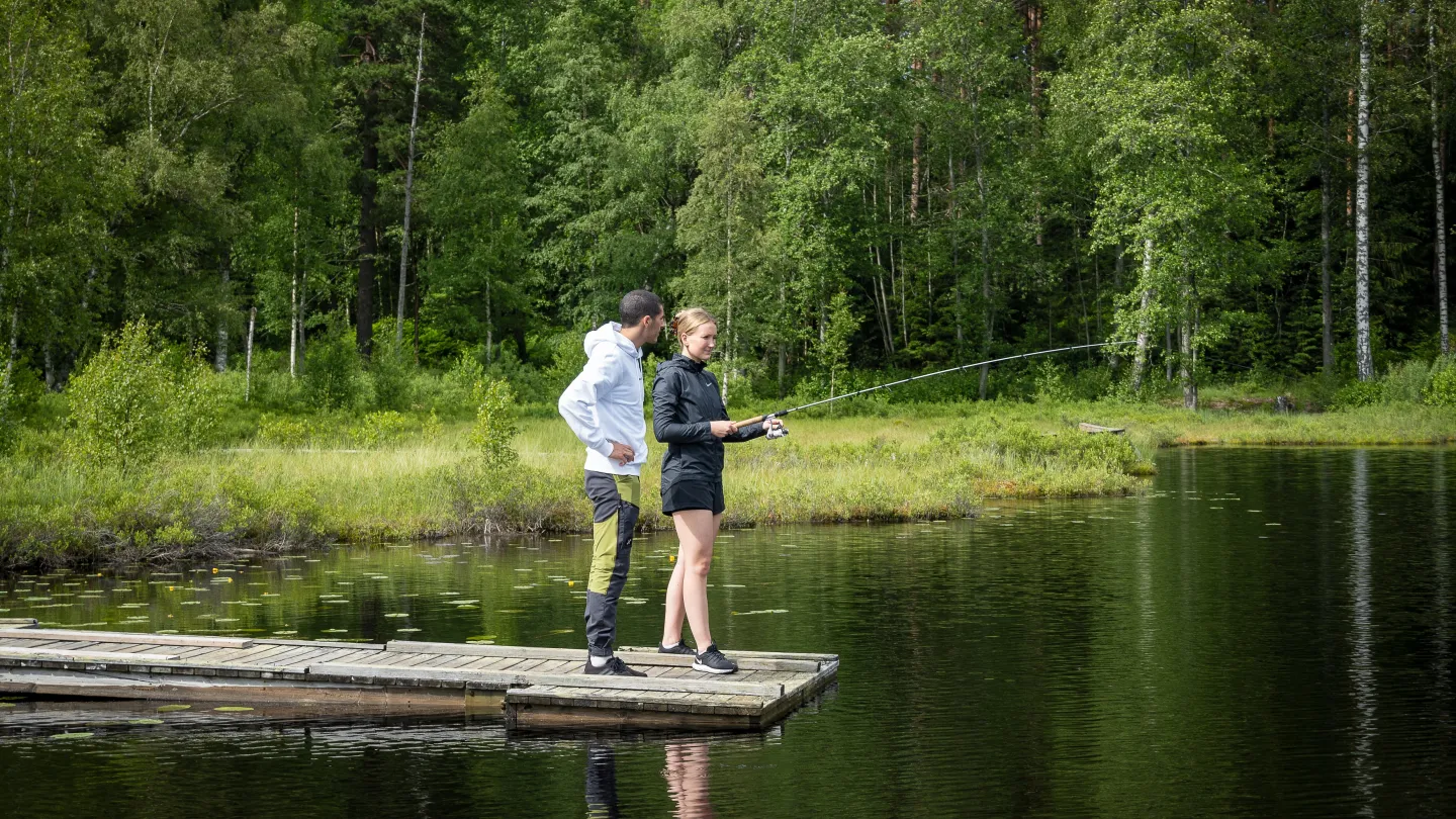 Ett par som står på brygga och fiskar.