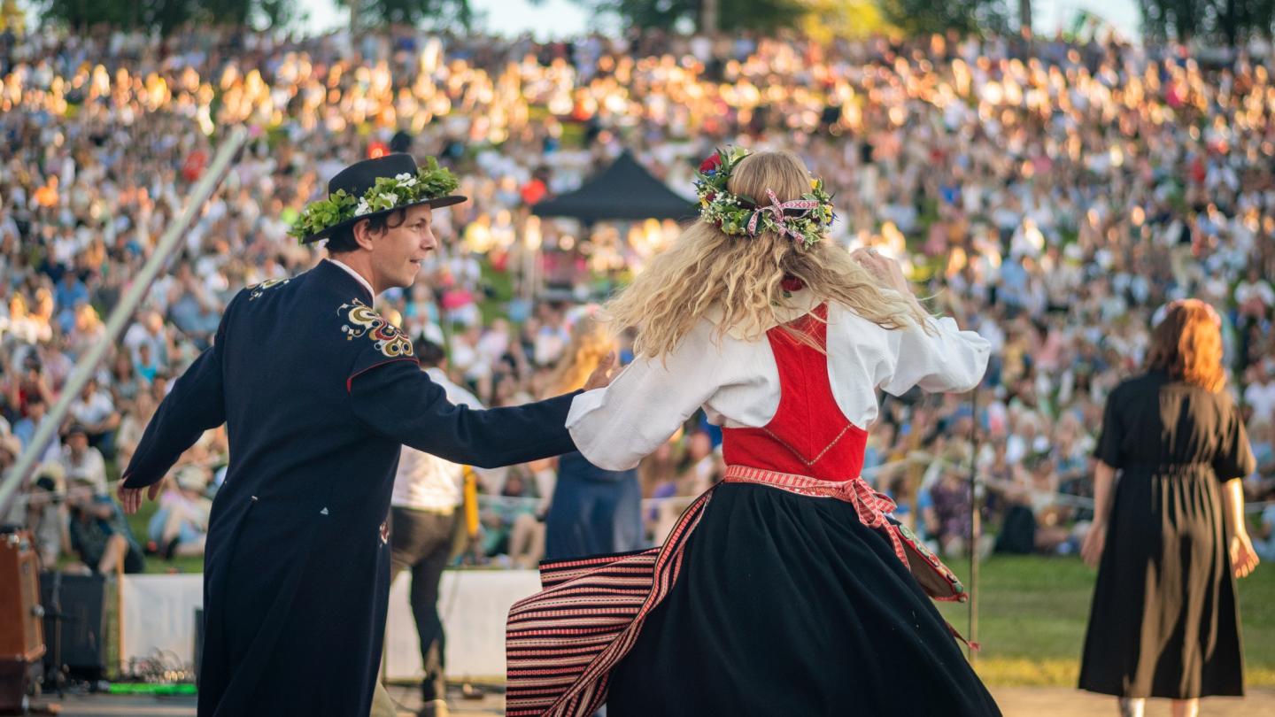 Couple in folk costume performing during midsummer celebration.