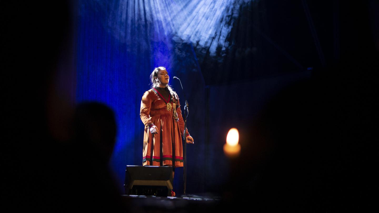Samisk kvinna i dräkt sjunger på scen.